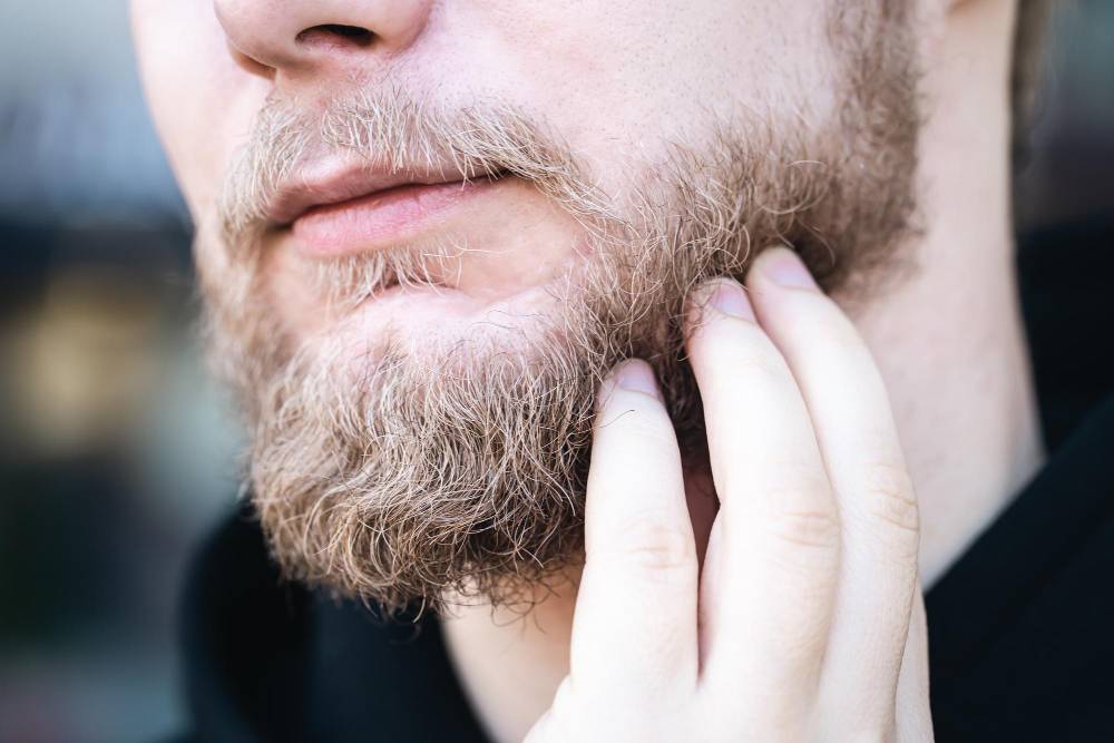 closeup-young-man-touches-his-beard-with-his-hand